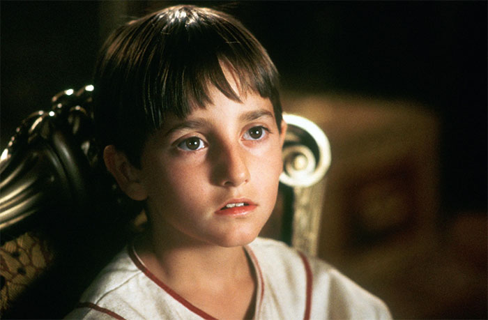 Young former Hollywood star sitting on an ornate chair, illustrating former stars who left the spotlight for normal careers.