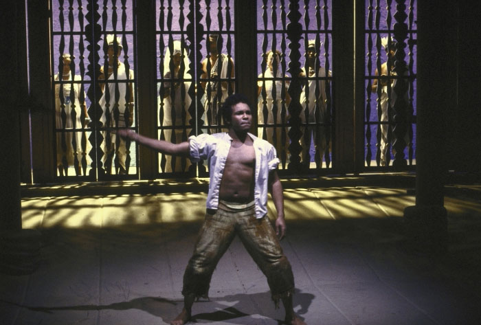 Man performing in front of bars with a group behind him, representing former Hollywood stars who left the spotlight.