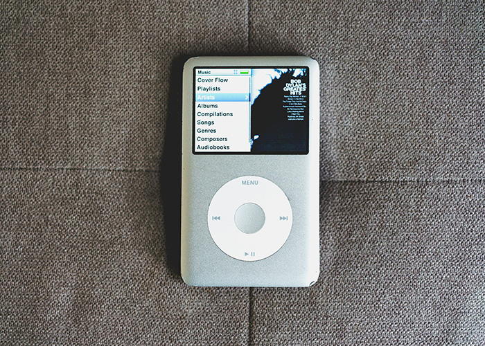 Classic iPod device still in use, showcasing playlists and music options on screen, representing obsolete tech usage.