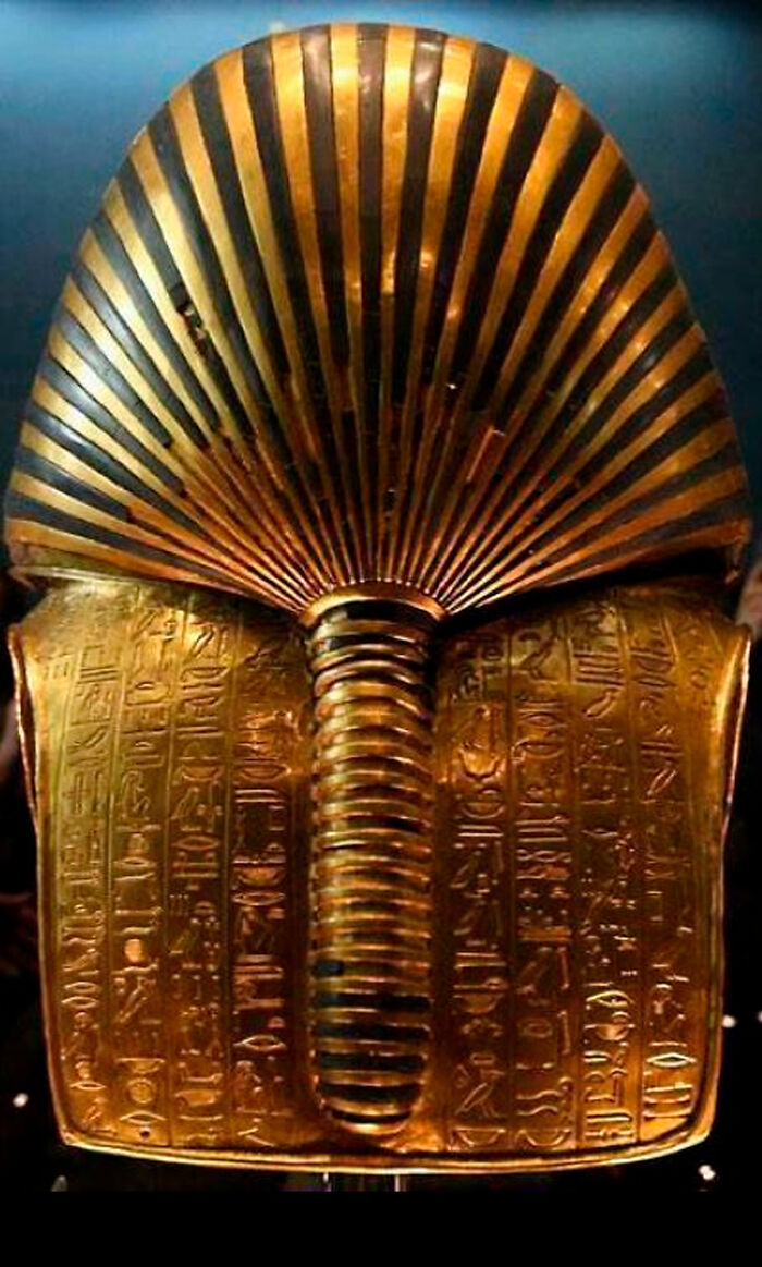 Golden ancient Egyptian mask with intricate hieroglyphs shown from a unique angle among famous landmarks.