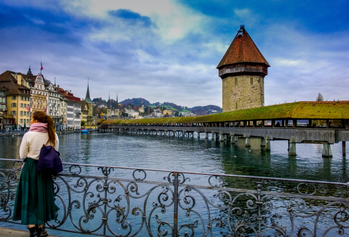 Woman overlooking historic wooden bridge and scenic riverside views in one of the best countries to live in 2025.