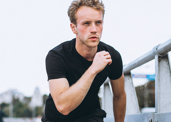 Young man in a black shirt running outdoors with a focused expression, representing unhinged comments about looks in public.