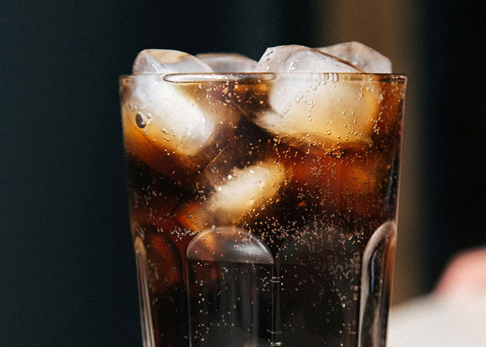 Close-up of a glass filled with a cold fizzy drink and ice, symbolizing awkward dates and stressed waitstaff moments.