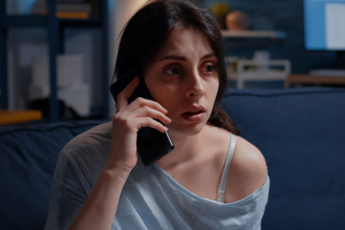 Worried woman making a phone call, reflecting on regret after man ends up in the hospital.