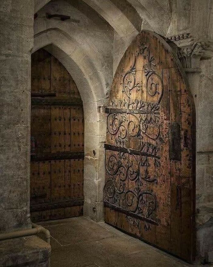 Archaeology world image of an ancient wooden door with intricate ironwork inside a stone building corridor.