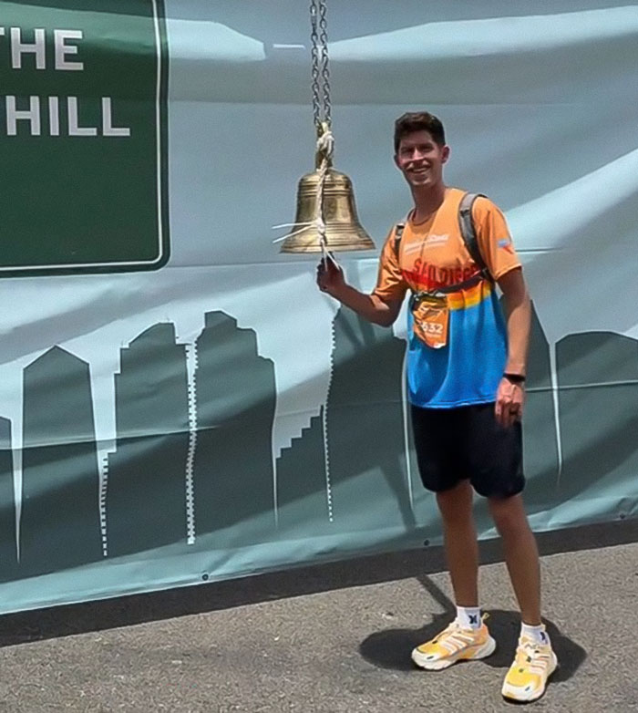 Man ringing a bell at marathon finish line after being signed up with just 24 hours notice and zero training