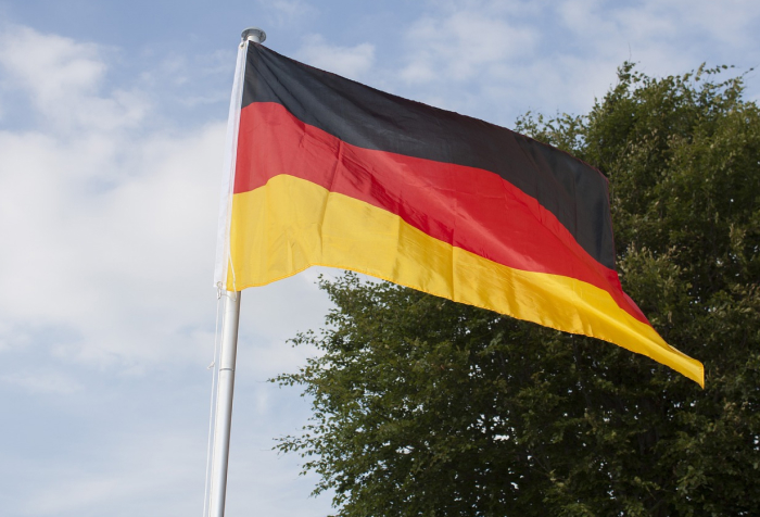 German flag waving on a pole against a partly cloudy sky, representing one of the best countries to live in 2025
