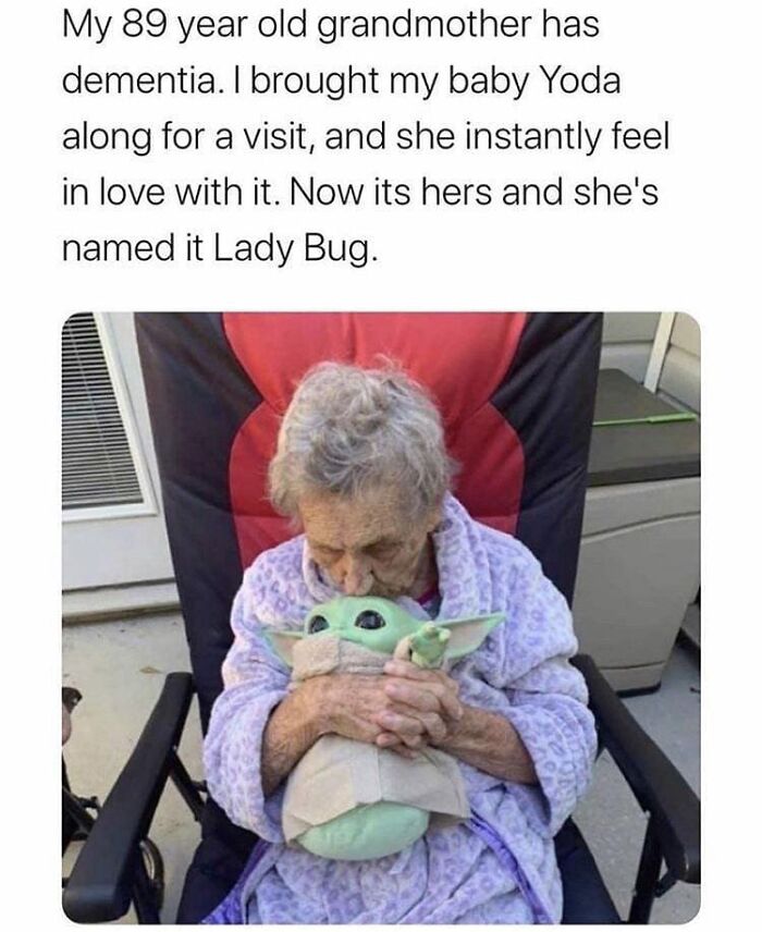 Elderly woman with dementia holding and hugging a Baby Yoda toy, showcasing wholesome feel-good moments.