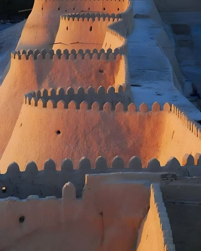 Ancient fortress walls with crenellations illuminated by sunlight, showcasing historical architecture in archaeology world.