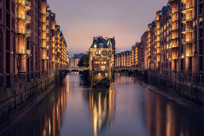Evening view of illuminated historic buildings and calm water canal, showcasing breathtaking travel photography.