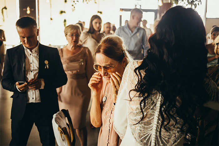 Woman at chaotic wedding event, reacting emotionally as people mingle in a crowded, lively wedding reception.