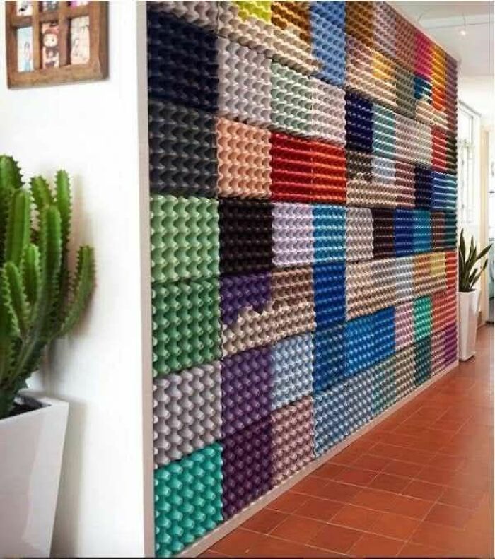 Colorful DIY craft wall made of egg cartons in a hallway, showcasing a creative but questionable craft shaming project.