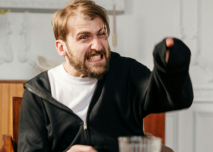 Angry man in a black jacket yelling with frustration during an awkward date, capturing painful and tense emotions.