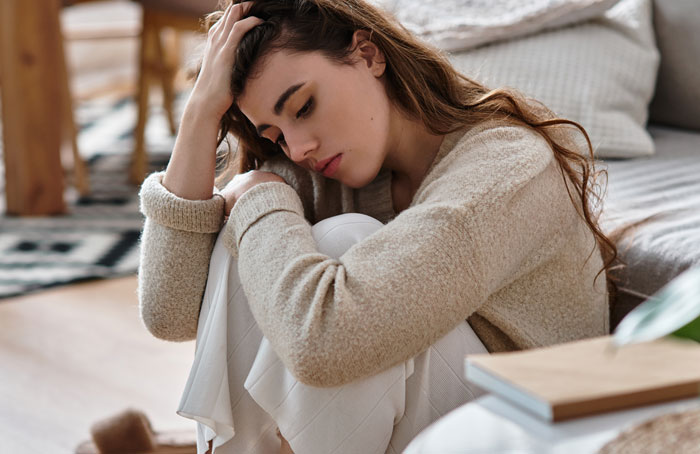 Sad woman sitting on the floor, deep in thought, reflecting on regrets after her husband ends up in the hospital.