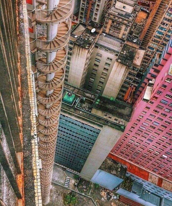 Spiral death stairs on the side of a tall building, showing a dizzying and dangerous height among urban rooftops.