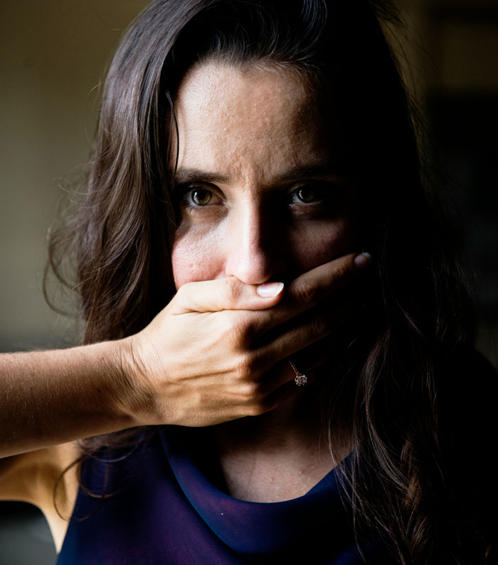 Woman with long dark hair covering her mouth, illustrating a surprisingly effective old wives' tale remedy in natural light.