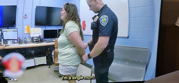 Single mom being handcuffed by police in office room, illustrating entitled behavior and refusal to pay responsibilities.