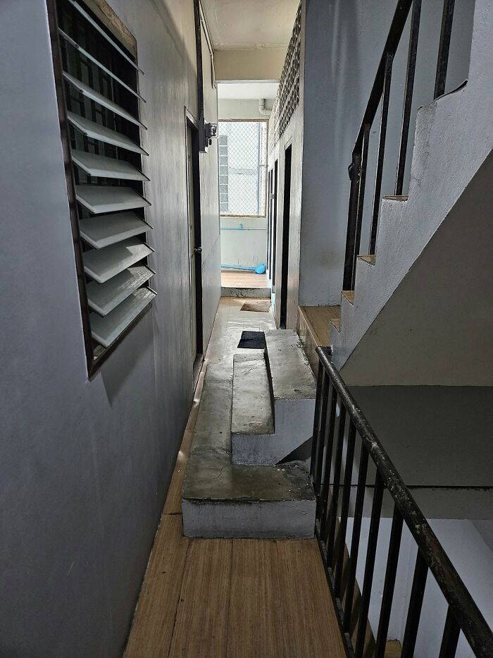 Narrow hallway with uneven concrete death stairs posing a hazardous and awkward climbing challenge inside a building.