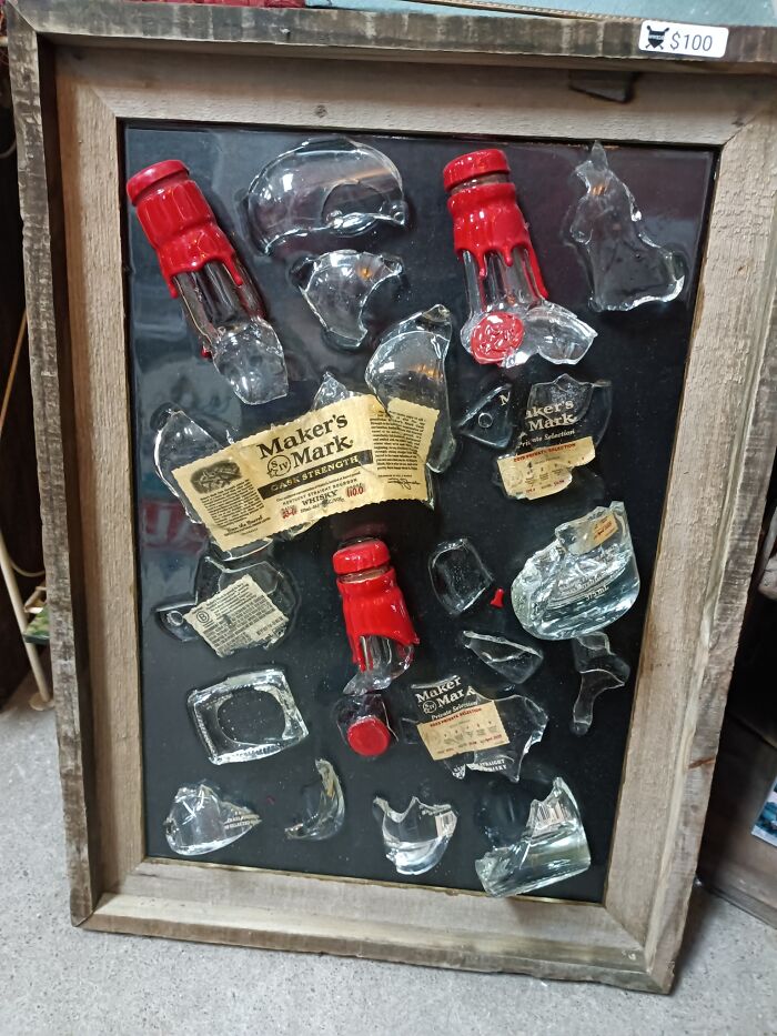 Broken Maker’s Mark bottle pieces displayed in a wooden frame as a craft shaming DIY project gone wrong.