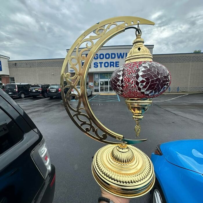 Vintage decorative lamp held outside Goodwill, showcasing cool secondhand finds in a parking lot setting.