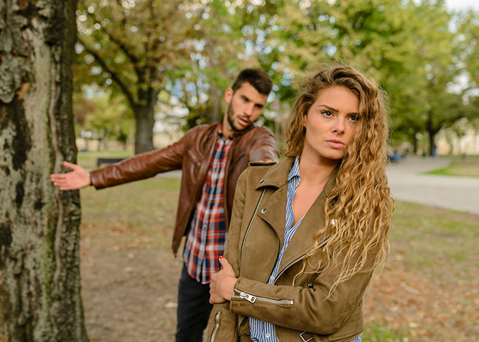 Couple in park showing tension and disagreement, illustrating emotional moments related to called off engagements.