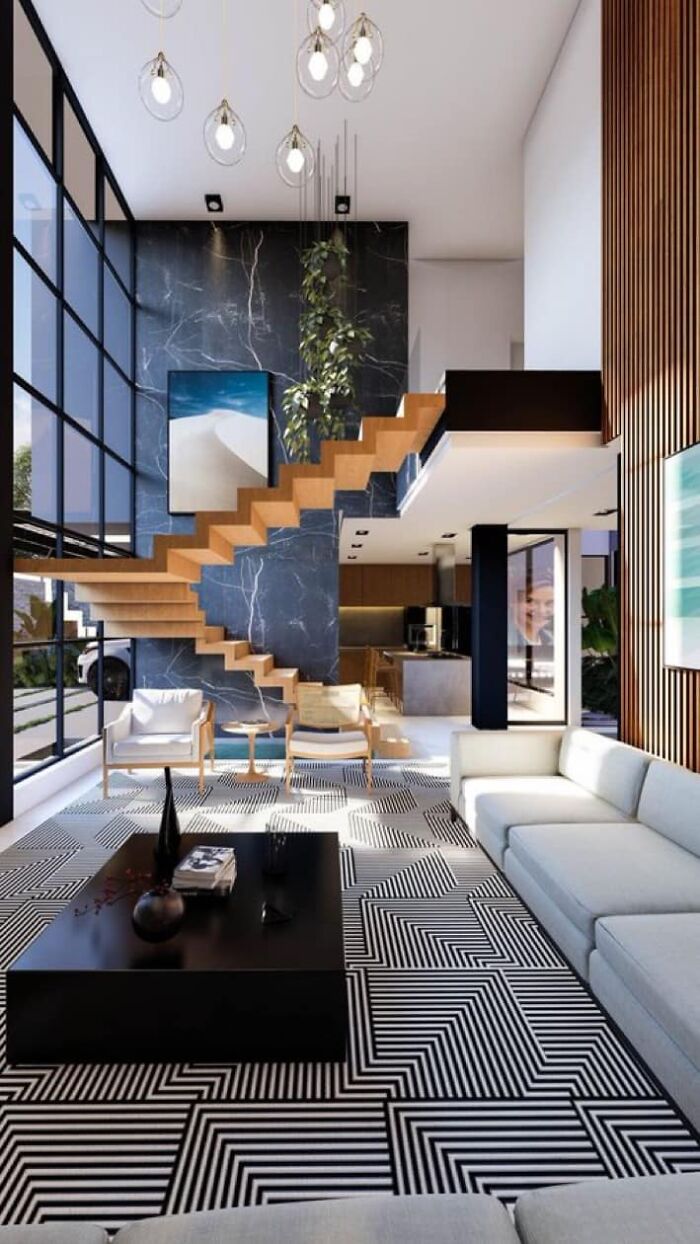 Modern living room with geometric carpet and striking floating wooden death stairs against a dark marble accent wall.