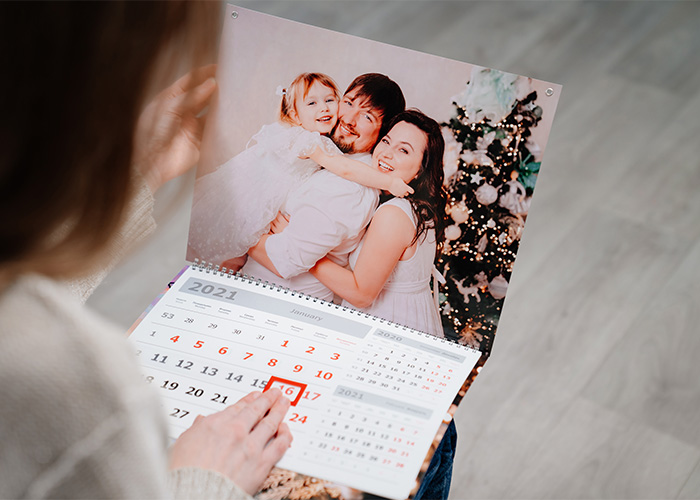 Person holding a printed 2021 calendar featuring a family photo, illustrating still use daily of obsolete items.