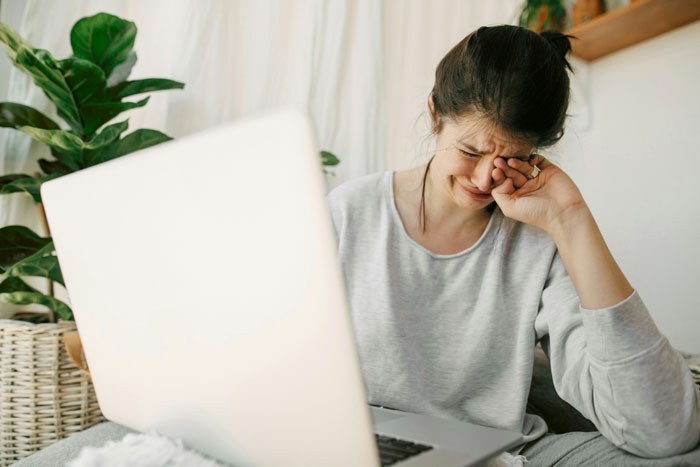 Woman wiping tears during an online therapy session, experiencing emotional revelations related to therapy insights and personal healing.