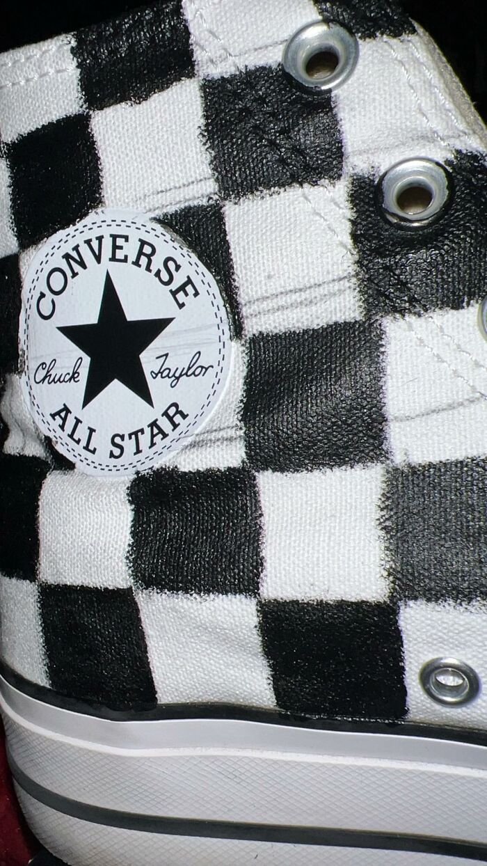 Close-up of a black and white checkered Converse All Star sneaker with metal eyelets and visible stitching.