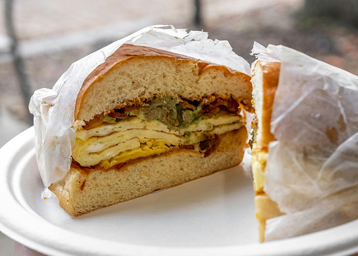 Breakfast sandwich on a white plate showing eggs and avocado, unrelated to dads sharing birthing room experiences.