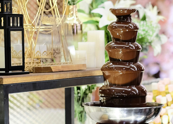 Chocolate fountain at a buffet with decorative candles and flowers, illustrating wildest encounters of buffet workers.