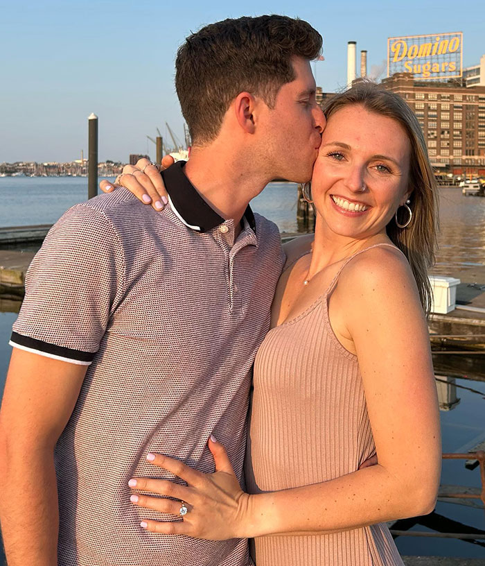 Couple by waterfront with woman smiling as husband kisses her, symbolizing marathon sign-up with zero training.