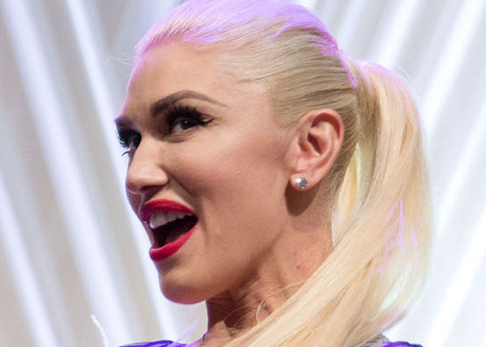 Close-up of a blonde woman with bright red lipstick smiling and speaking, illustrating celebrities before fame stories.