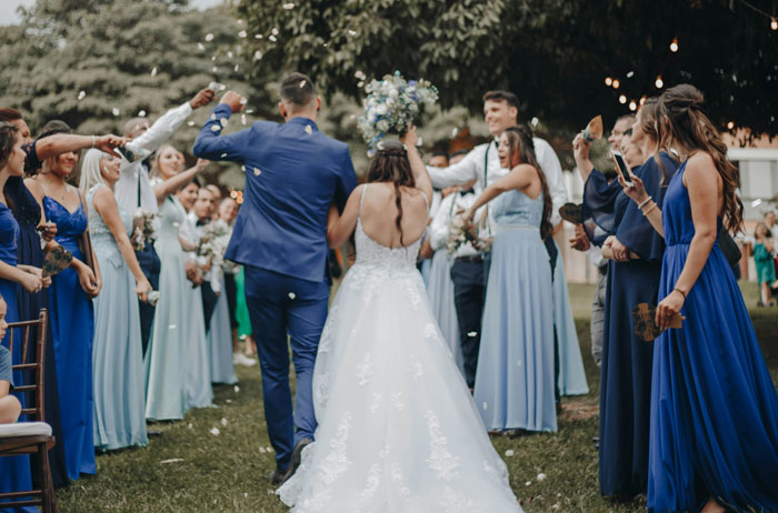 Bride in white gown celebrating with groom and guests outdoors, highlighting pets replacing kids at wedding ceremony.