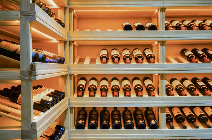 Wine bottles stored in a luxurious wooden cellar showcasing the extravagant lifestyle of out-of-touch rich people flaunting wealth.