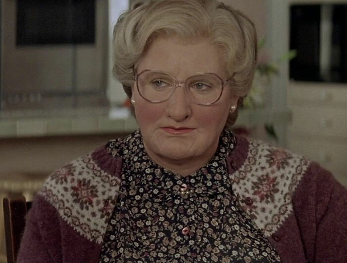 Close-up of a character in a patterned sweater and glasses, representing scenes from romantic but toxic movies.