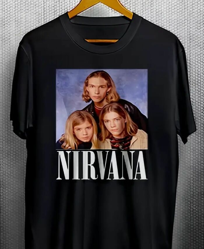 Black T-shirt with a flawed DIY Nirvana band print design hanging on a wooden hanger for craft shaming.