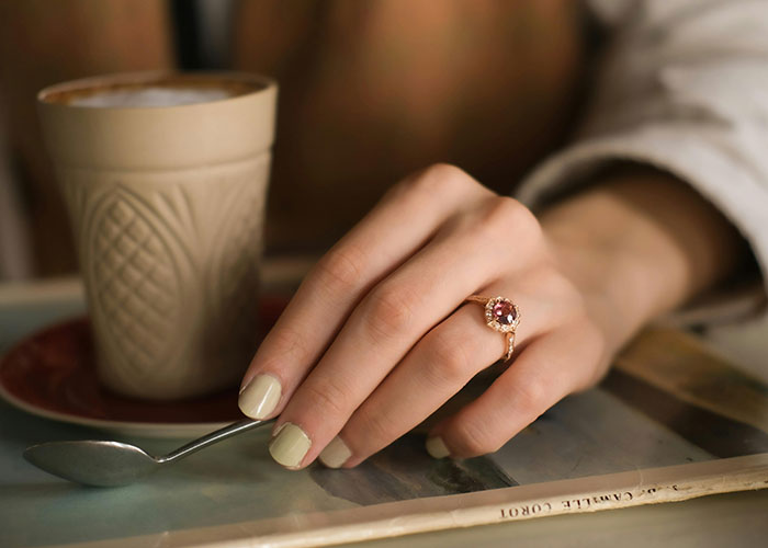 Close-up of a hand with a ring resting next to a coffee cup, evoking the awkwardness of painful and awkward dates.