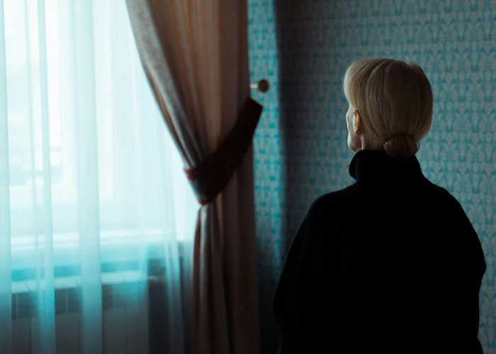 Woman standing by a window in a dim room, reflecting on reasons why they called off their engagement.