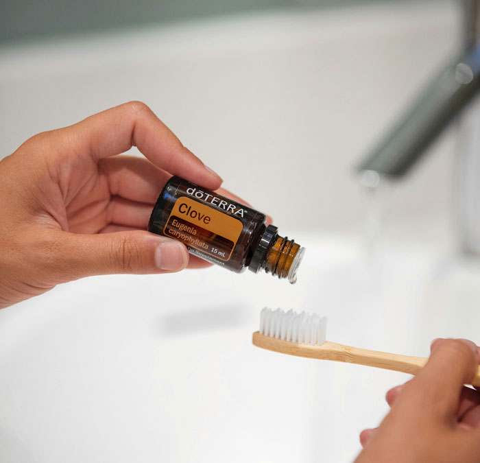 Hand applying clove essential oil to a toothbrush, demonstrating surprisingly effective old wives' tales remedies.