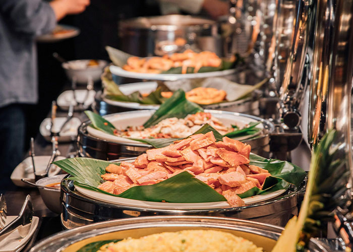 Buffet workers serving various dishes at a buffet line, showcasing wildest encounters and busy food service.