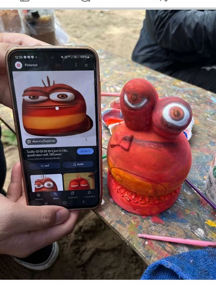 Hand holding phone showing original cartoon next to a poorly crafted DIY figure of the same character, craft shaming fail.