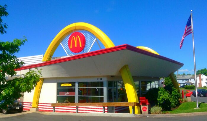 McDonald's restaurant exterior with yellow arches and an American flag representing industries hit by millennials.