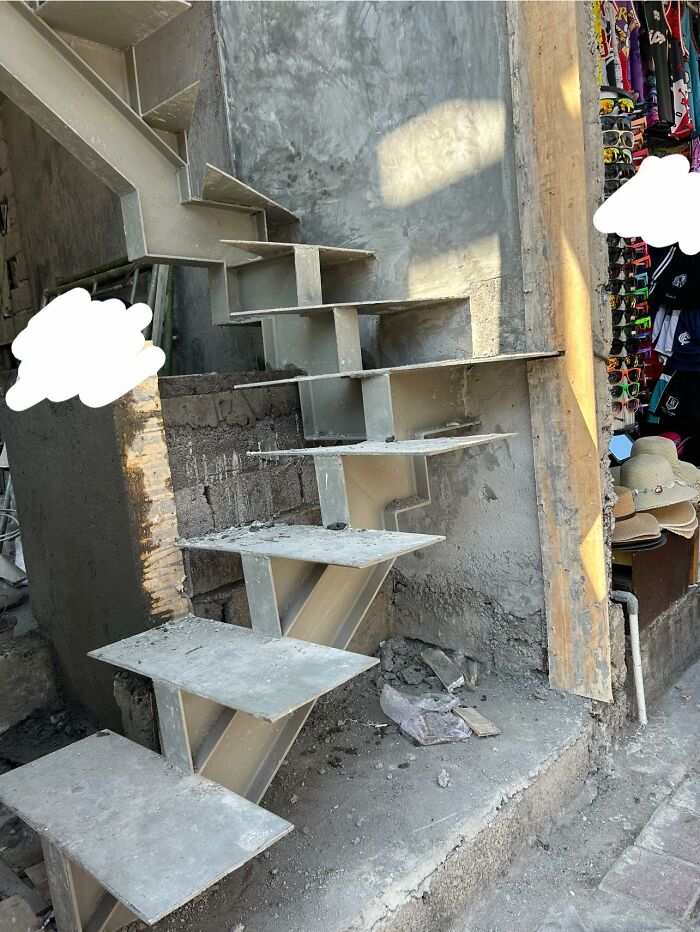 Unfinished concrete death stairs with uneven steps and no railing, posing a dangerous climbing hazard in construction area.