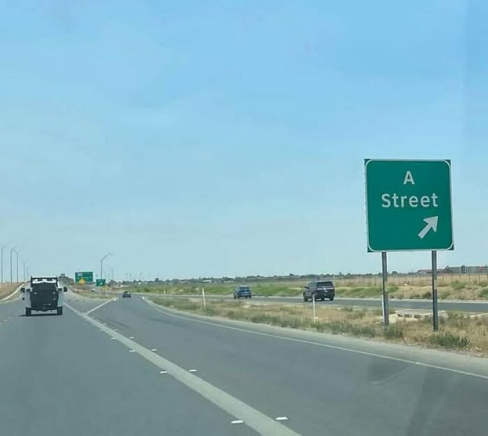 Road sign for A Street exit on a clear highway, showing one of the hilarious signs adding chaos to the world.