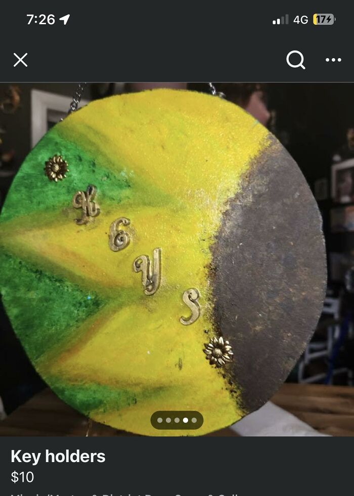 Round handmade key holder painted green and yellow with misaligned letters, showcasing a horrendous DIY craft project.