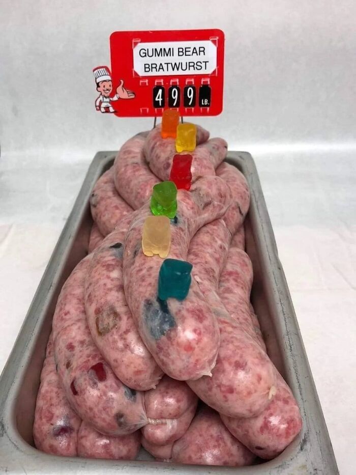 Tray of raw bratwurst sausages with gummy bears inserted, creating a cursed food image that might make you say eeeeuw.