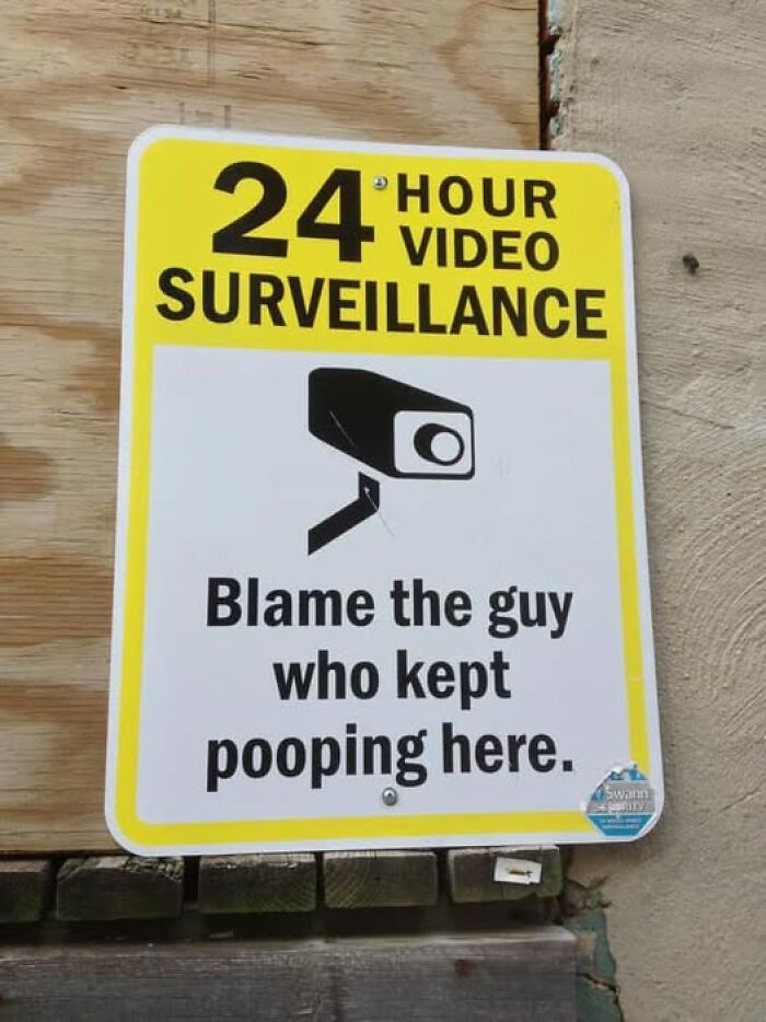 Funny surveillance sign blaming the guy who kept pooping here, adding chaos with hilarious warning humor.
