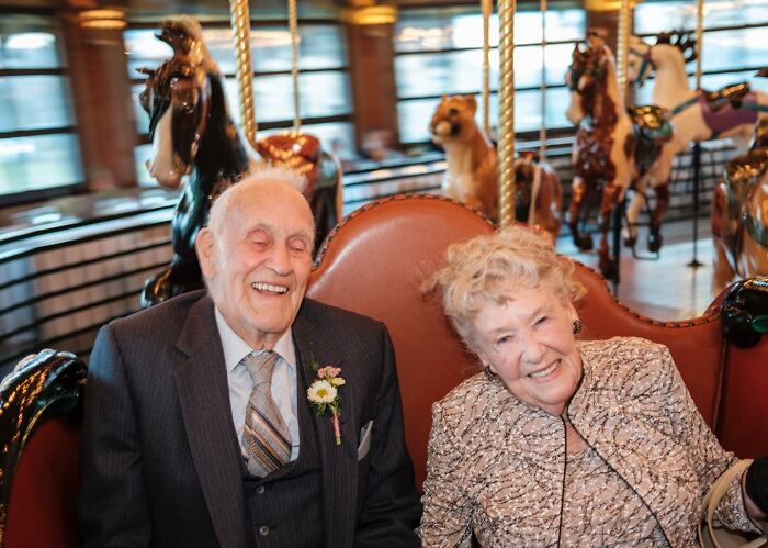 Elderly couple smiling happily while seated on a carousel, a charming unforgettable wedding photo moment.