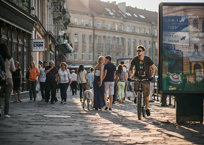 Crowded street scene with people walking, a cyclist passing by, capturing creepy facts shared by 83 people in urban setting.